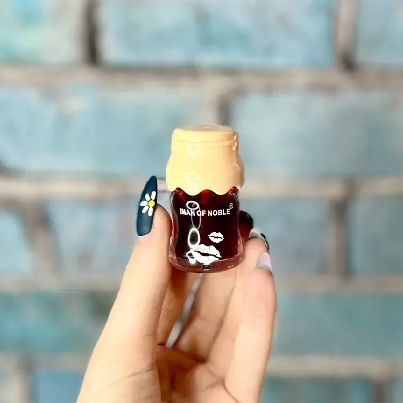 Женская рука держит тинт IMAN OF NOBLE