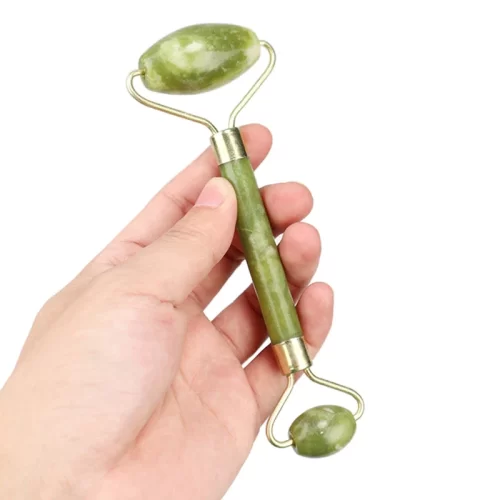 Рука держит кварцевый ролик для массажа лица Гуа Ша